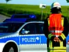 Ein Feuerwehrmann in Montur vor einem Polizeiauto