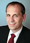 Abbildung Norbert Steffens, Hexagon GmbH, dunkler Anzug, weißes Hemd, dunkelrote Krawatte