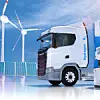 Ein mit grünem Wasserstoff betriebener LKW steht an einer H2-Tankstelle. Im Hintergrund stehen Photovoltaikanlagen und Windkraftanlagen.