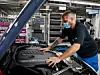 Ein BMW-Mitarbeiter, der Maske trägt, überprüft in einem Werk ein Auto.