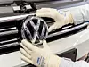 VW-Mitarbeiter bringt das Markenlogo an einem Neuwagen an.