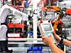 Ingenieur kontrolliert Roboterarm beim Verpackungsprozess von Lagern in der Automobilindustrie.