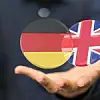 Mann hält Hand nach vorne. Darauf schweben die Flaggen von Deutschland und Großbritannien