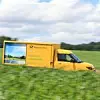 Elektroauto der deutschen post fährt durch ein Feld