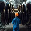 Bauarbeiter mit orangem Helm vor Gasturbine