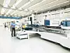 Einblick in die Smart Factory von Trumpf in Ditzingen: Mann steht mit Tablet an der Steuerung einer Maschine. Die Maschine ist Teil einer Reihe von Blechbearbeitungsmaschinen.