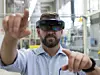 Ein Mann trägt eine Hololens und gestikuliert mit seinen Händen in Richtung Kamera.