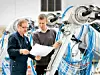 Zwei Dürr-Mitarbeiter schauen sich vor einer Maschine eine Skizze an.