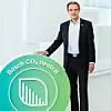 Bosch Chef Volkmar Denner steht neben einem übergroßen Logo mit der Aufschrift CO2-neutral.