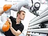 Ein Kuka-Mitarbeiter arbeitet mit einem Roboter des Unternehmens.
