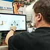 Ein Kuka-Mitarbeiter bedient einen Roboter über ein Display