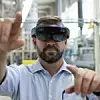 Ein Mann trägt eine Hololens und gestikuliert mit seinen Händen in Richtung Kamera.