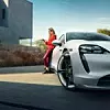 Frau, die an einem Porsche Taycan lehnt.