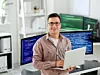 IT-Ingenieur vor Bildschirmen mit Laptop in den Händen