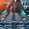 Mann in einer Produktionsstätte steht vor einer Batterie für Elektroautos