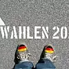 Zwei Schuhe mit Deutschlandflaggen. Auf dem Boden steht ein Pfeil und