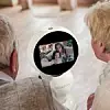 Zwei Senioren schauen zu einem Roboter, auf dem per Video eine Frau und ein Kind zugeschalten sind.