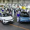 VW Mitarbeiter aus Zwickau stehen mit dem Golf und dem Id3 im Werk