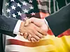 Händeschütteln vor Flaggen der USA und Deutschlands