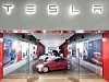 Ein Tesla-Store von außen. Im Store steht ein rotes Auto.