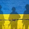 Flagge der Ukraine, gemalt auf einer Backsteinmauer mit Soldatenschatten.