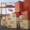 Auf einem Containerhafen liegen neben Containern Kisten, auf denen die chinesische Flagge sowie