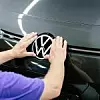 VW Logo wird im Werk von einem Werker angebracht