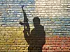 Flaggen von Russland und der Ukraine auf einer Mauer, davor Schatten eines Soldaten