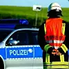 Feuerwehrmann steht vor Polizeiauto