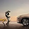 Zwei Roboter von Boston Dynamics stehen einem Hyundai-Fahrzeug gegenüber.