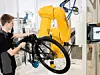 Monteur arbeitet mit einem Cobot zusammen an einen Fahrrad