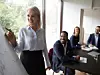 Frau die Kollegen etwas auf einem Whiteboard zeigt.