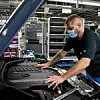 Ein BMW-Mitarbeiter, der Maske trägt, überprüft in einem Werk ein Auto.