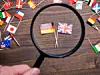 Deutsche und britische Flagge, die mit einer Lupe angeschaut werden.