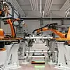 Mehrere orangene Kuka-Roboter arbeiten in einem Werk.
