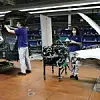 Zwei VW-Mitarbeiter arbeiten in einem Werk an zwei Autos.