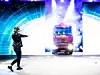 Ein Lkw ist im Scheinwerferlicht auf einer Bühne. Eine Person trägt eine Augmented Reality Brille und zeigt zum Lastwagen.