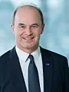 Portrait von Martin Brudermüller, Vorstandsvorsitzender BASF; lächelnder Mann mit dunklen Haaren und Halbglatze, er trägt einen dunklen Anzug mit blauer Krawatte