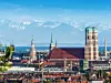 Blick auf Münchner Frauenkirche. Bergpanorama im Hintergrund.