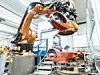 Orangefarbener Kuka Roboter bei der Arbeit in einer Werkhalle