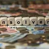 Symbolbild Insolvenz, Insolvenzreport Falkensteg: Münzen und Geldscheine, darauf buchstabieren Holzwürfel das Wort Insolvenz.