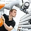 Ein Kuka-Mitarbeiter arbeitet mit einem Roboter des Unternehmens.
