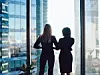 zwei Frauen schauen aus einem Fenster auf eine Skyline