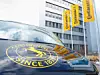 Dunkelblaues Auto mit dem gelben Continental Logo auf der Motorhaube steht vor dem Continental Gebäude. Im Hintergrund drei gelbe Conti-Flaggen.