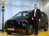 Continental Chef Elmar Degenhart posiert vor einem Elektroauto.
