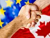 Zwei Menschen schütteln sich die Hand. Dahinter die Flaggen der EU und Kanadas