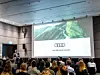 Geschäftsführer Rüdiger Recknagel spricht bei einer Veranstaltung vor zig Besuchern. Auf der Leinwand ist eine Folie der Audi-Stiftung für Umwelt zu sehen.