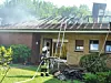 Ein Feuerwehr ist dabei, einen brennenden Bungalow zu löschen.