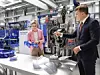 Dr. Nicole Hoffmeister-Kraut, die Wirtschaftsministerin von Baden-Württemberg, und Vorstandsvorsitzender Peter Fenkl schauen sich Bauteile des Unternehmens an.