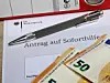 Antrag auf Soforthilfe plus zwei 50-Euro-Scheine und eine Kugelschreiber liegen auf einem Tisch